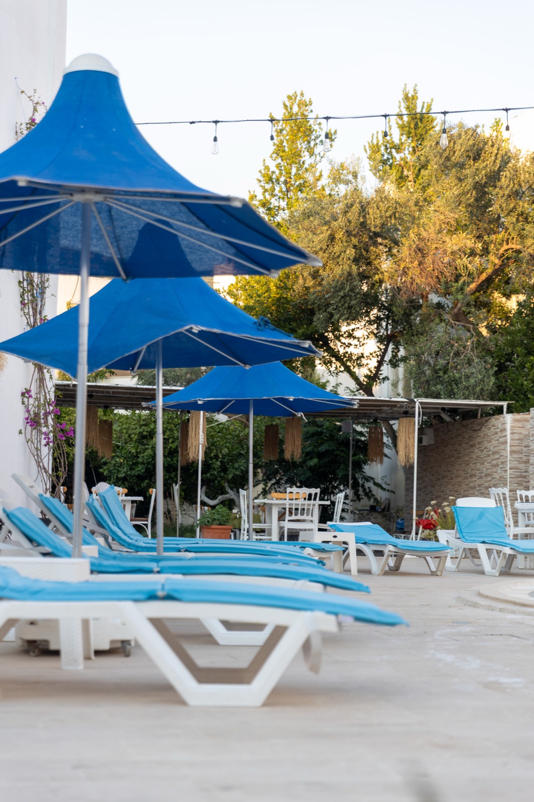 Mavi şemsiyeler ve şezlonglarla havuz terası